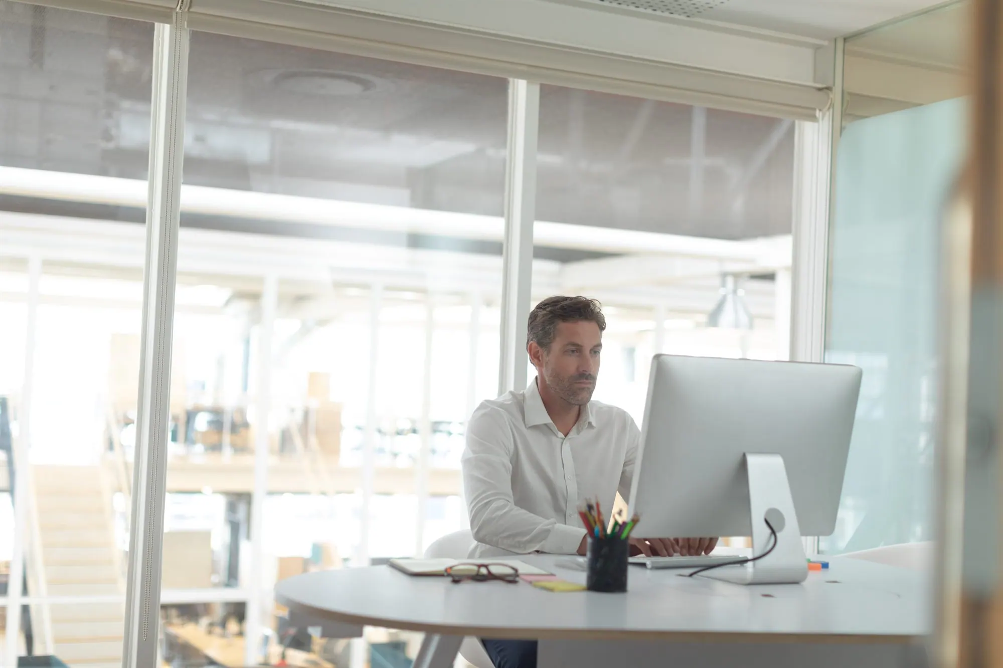 Person arbeitet konzentriert am Laptop in einem hellen, modernen Büro.