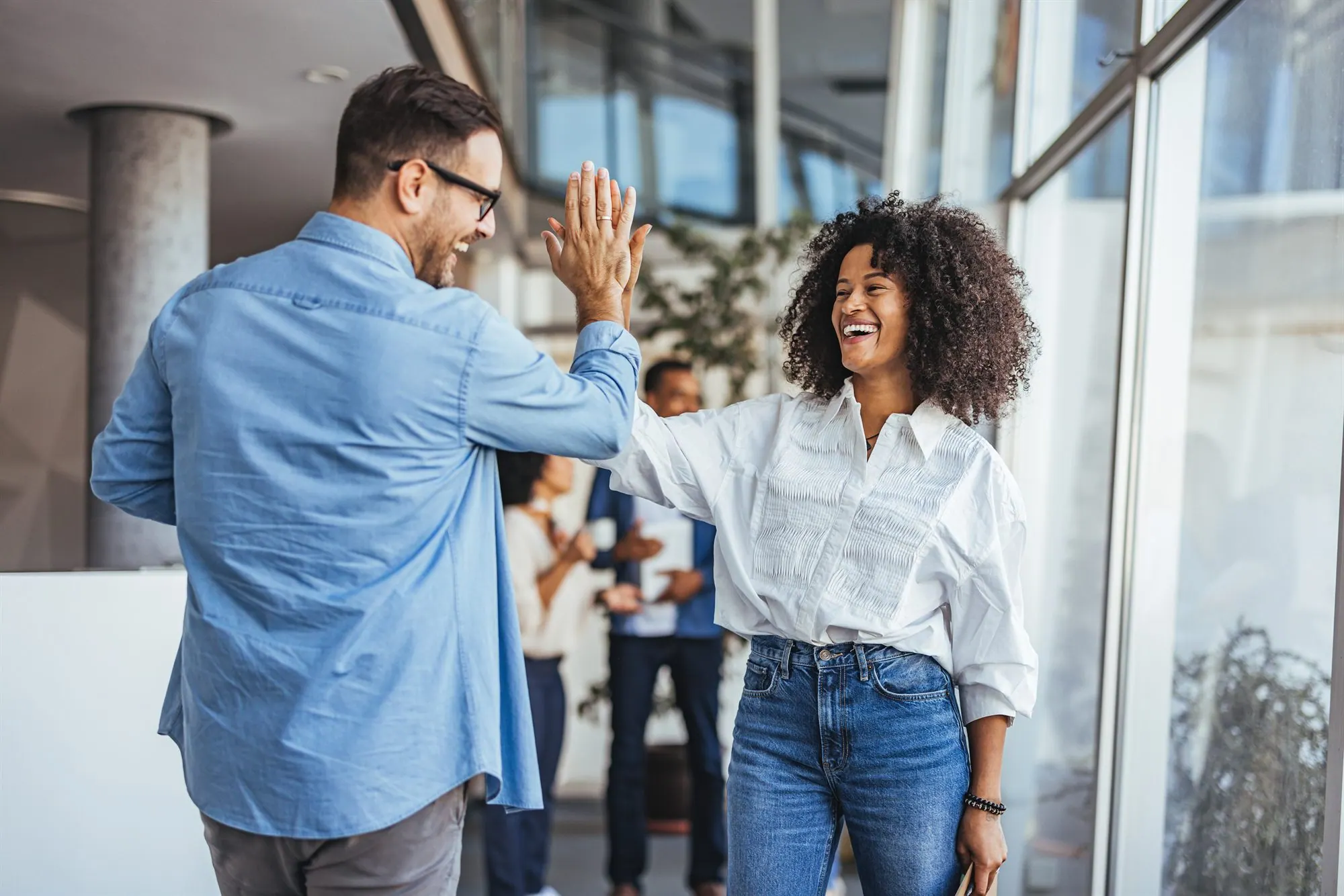 Zwei Kolleg:innen geben sich im Büro ein High-Five.